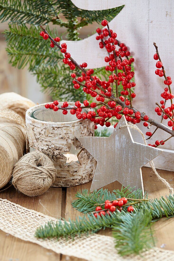 Weihnachtliche Dekoration mit Sternanhänger, Winterbeerenzweigen & rustikalem Windlicht