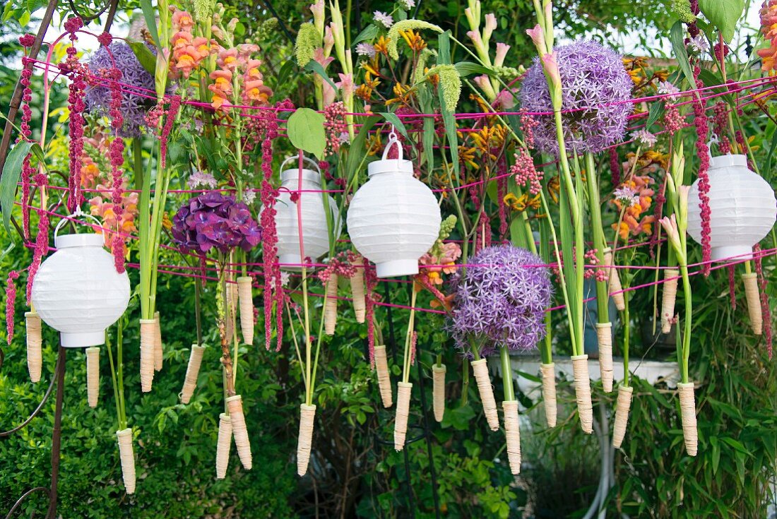 White lanterns and flowers hanging from washing line in garden