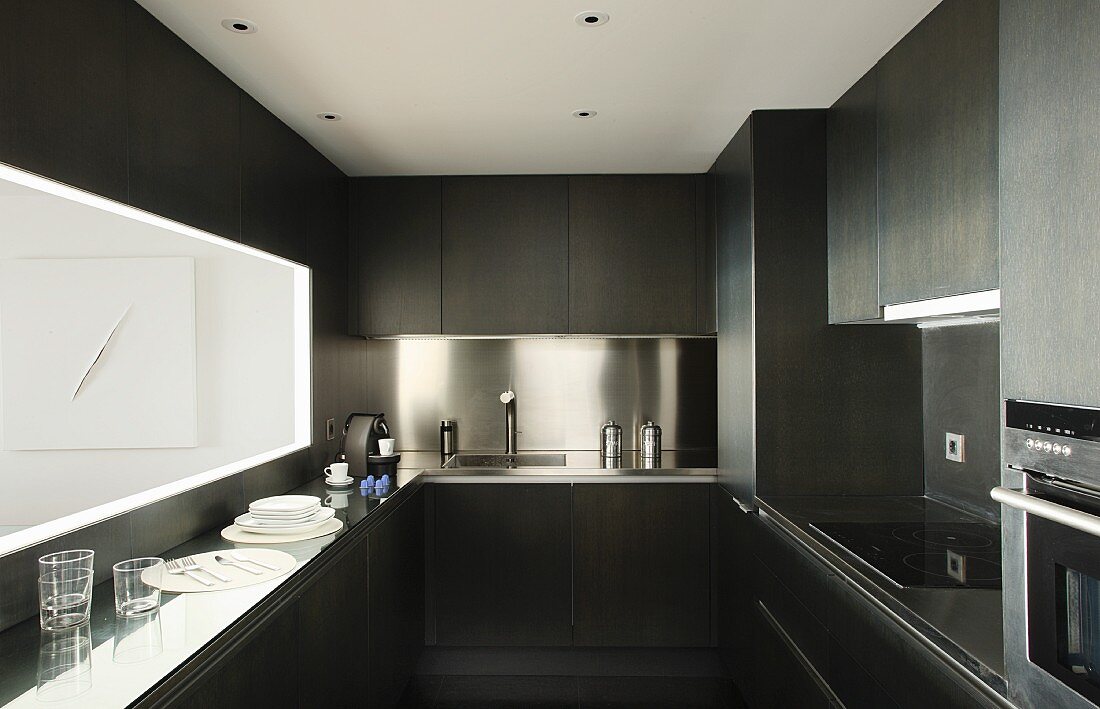 Dark designer kitchen with stainless steel splashback and hatch above narrow counter