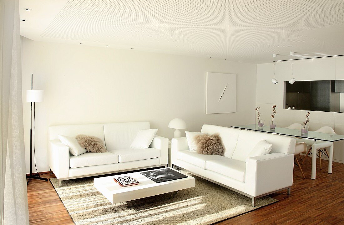 weiße Designermöbel im offenen Wohnraum mit Durchreiche zur Küche neben dem Essplatz
