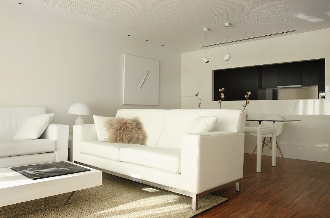 weiße Designermöbel im offenen Wohnraum mit Durchreiche zur Küche neben dem Essplatz
