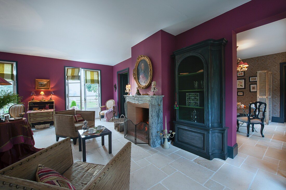 Fireplace next to black display cabinet in lounge with purple-painted wall and pale tiled floor