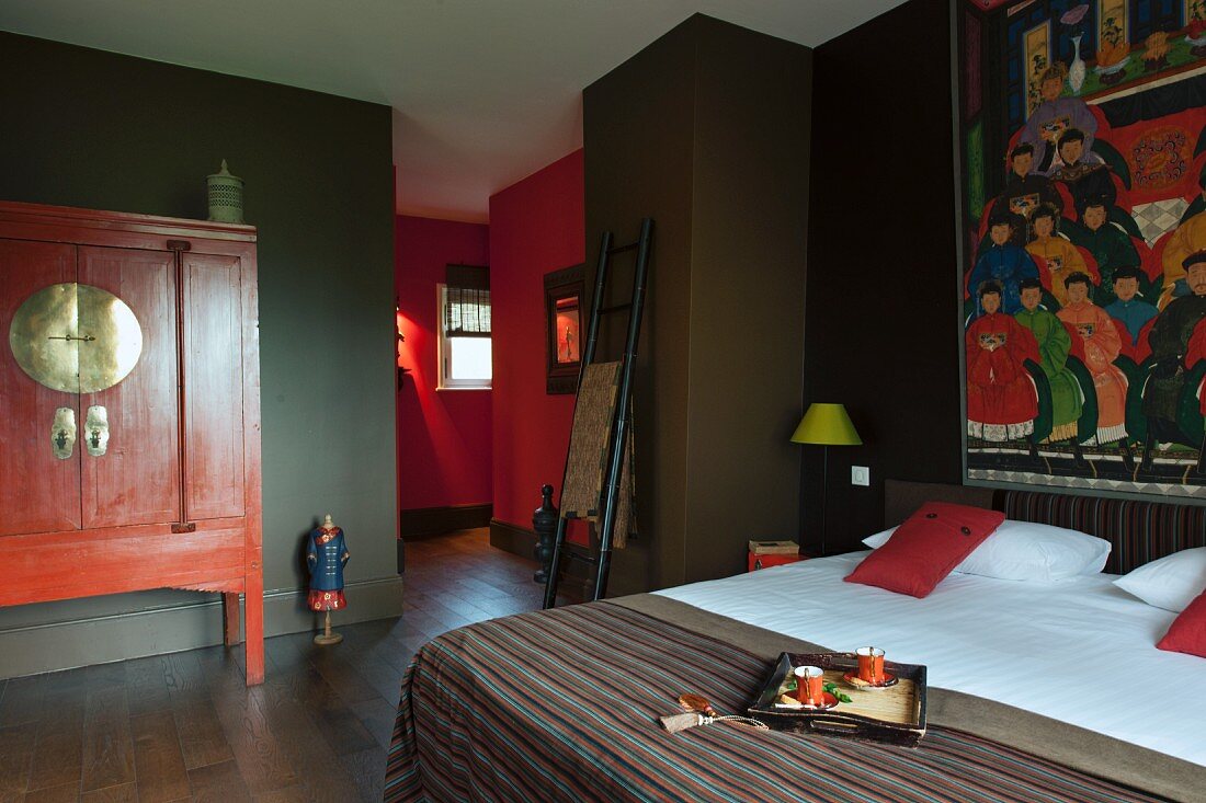 Schlafzimmer mit buntem Mandarin-Bild über Doppelbett, chinesischer Hochzeitsschrank mit Messingbeschlag