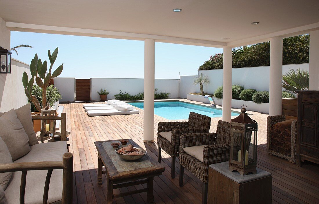 Rattan furniture on roofed terrace with pool in background