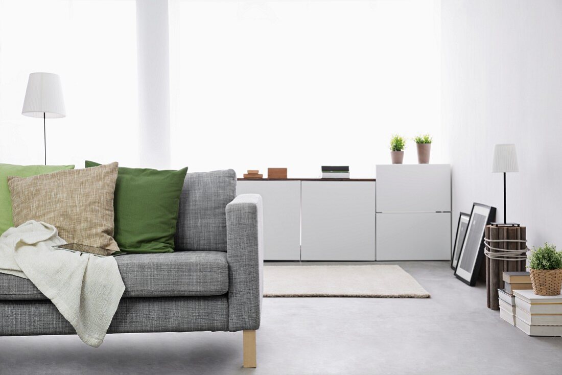 Moderner Wohnraum mit grau melierter Couch und weißem Sideboard im Hintergrund