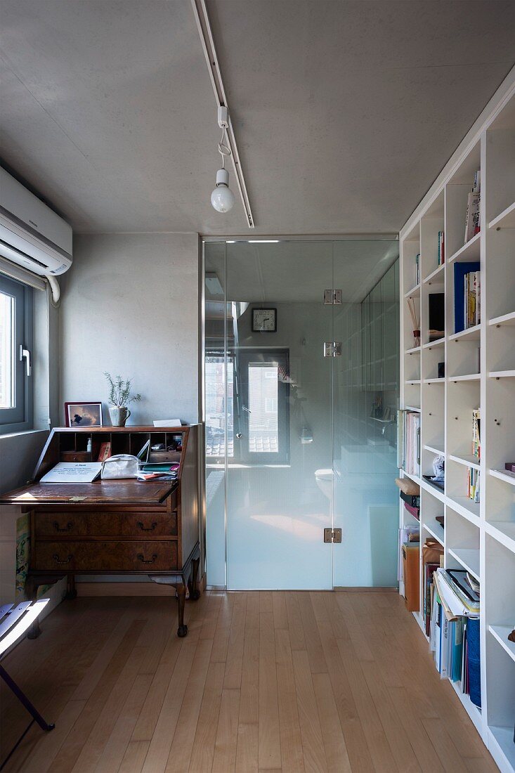 Office with antique bureau, fitted shelving and glass door leading to bathroom