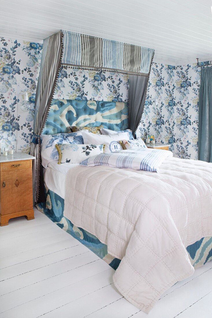 Half-tester double bed with striped canopy in romantic bedroom with blue floral wallpaper