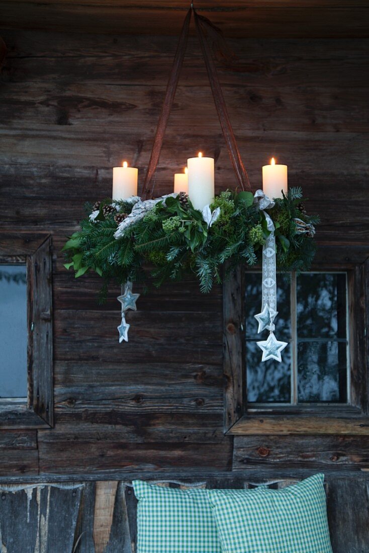 Rustic Advent wreath of fir branches hung in front of weathered wooden façade