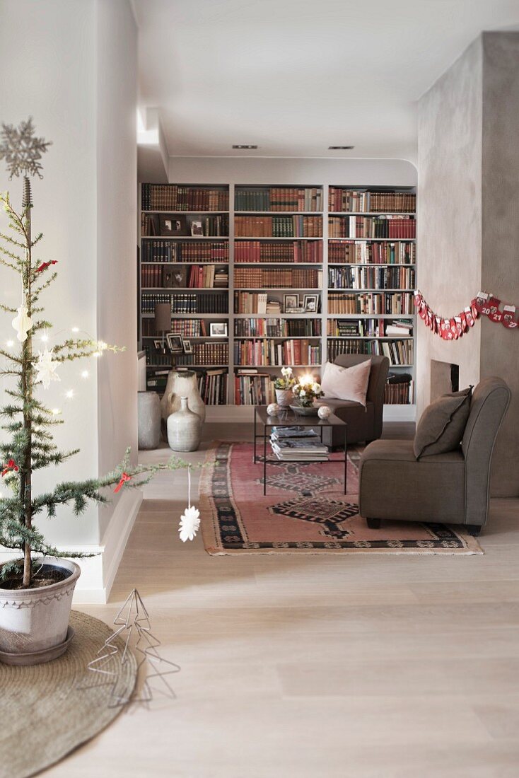 Langgestrecktes, weihnachtlich dekoriertes Wohnzimmer mit Bücherwand und Sitzbereich am Kamin