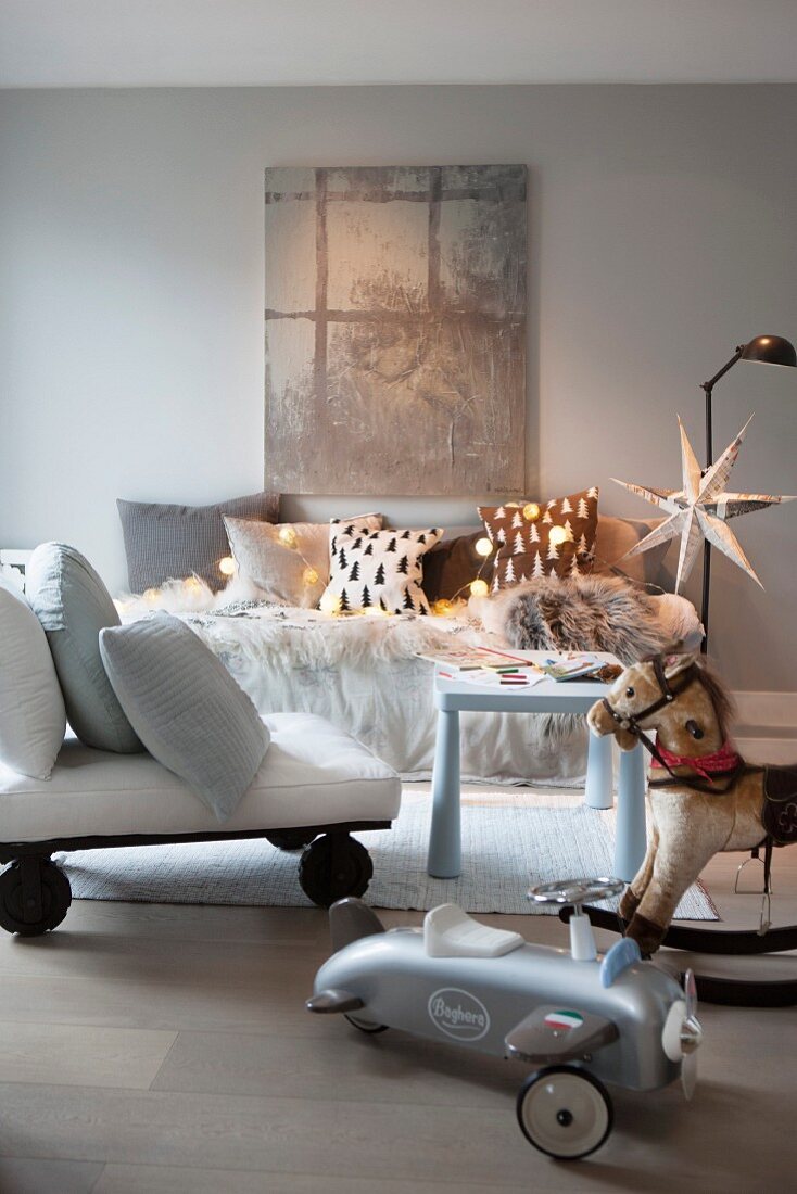 Weihnachtlich dekorierter Wohnraum mit Sofa, rollbarer Sitzgelegenheit, Schaukelpferd und Spielzeugauto
