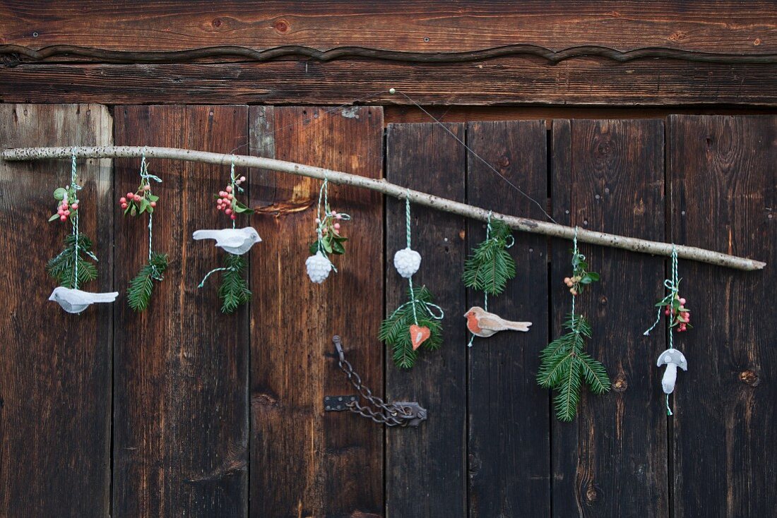 Selbstgebastelte Vogelanhänger aus Wollfilz mit Tannenzweigen an Ast weihnachtlich dekoriert