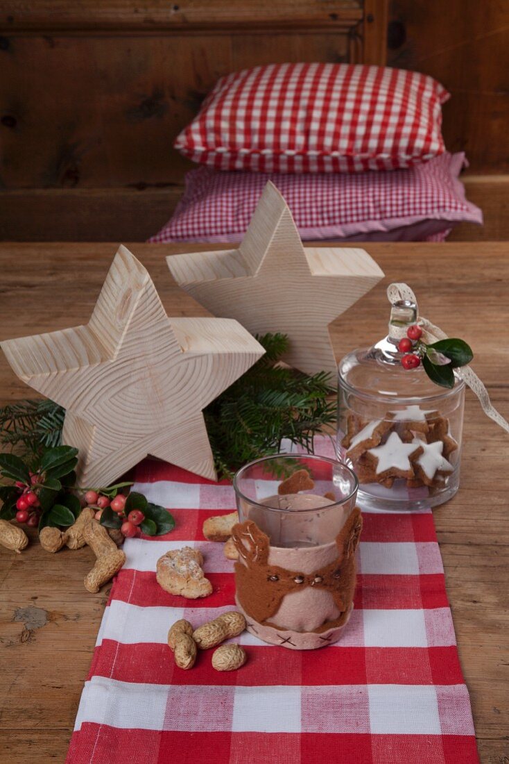 DIY-Glaswärmer aus Filz auf weihnachtlich dekoriertem Holztisch mit Holzsternen