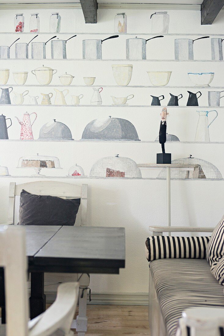 Esstisch und Sitzbank mit gestreiftem Bezug vor Wand mit Bemalung, Küchenmotive