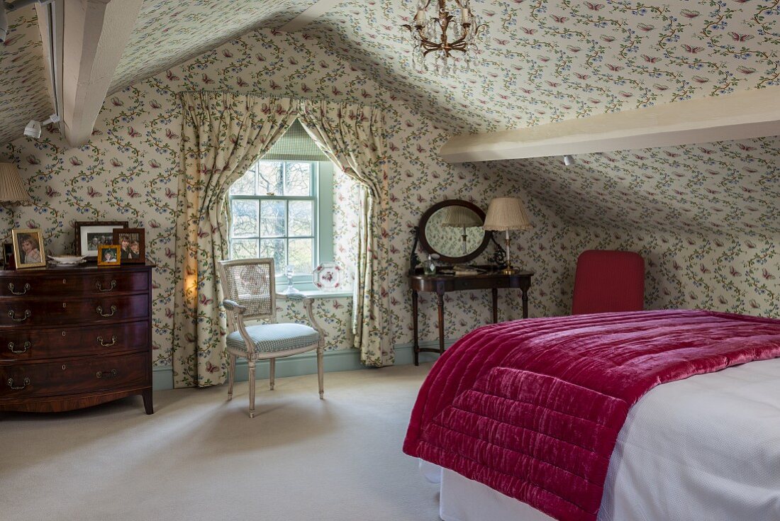 Schlafzimmer unter dem Dach im englischen Stil mit Blümchentapete an Wänden und Decke, Vorhänge mit gleichem Dessin