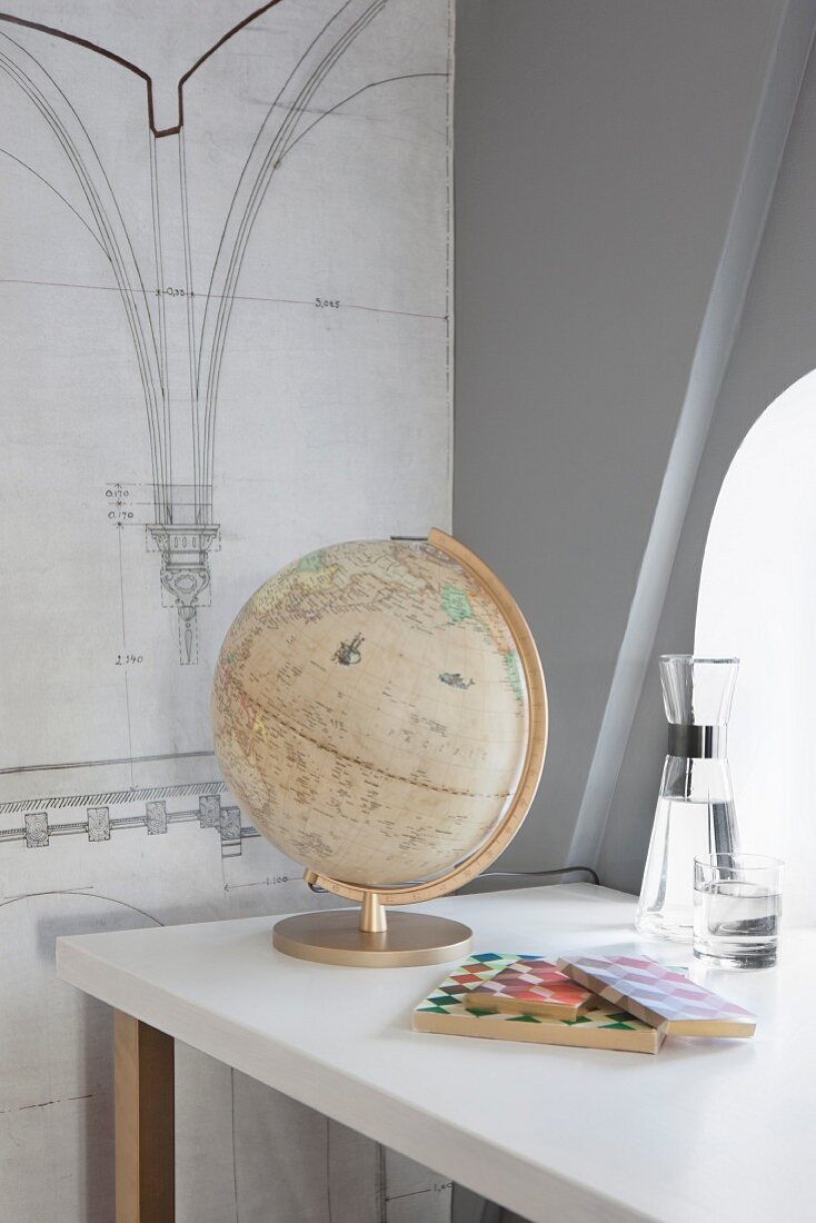 Vintage globe on desk and architectural drawing on wall