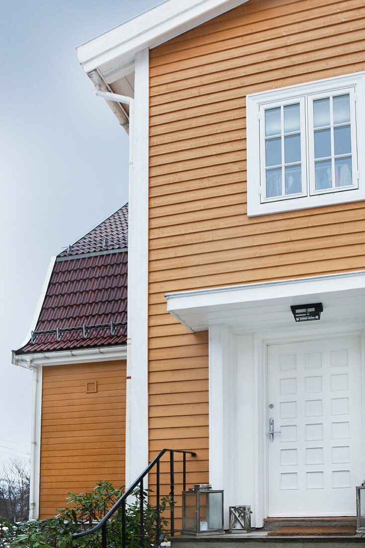 Elegantes Haus mit Holzverschalung und weißem, überdachtem Eingang