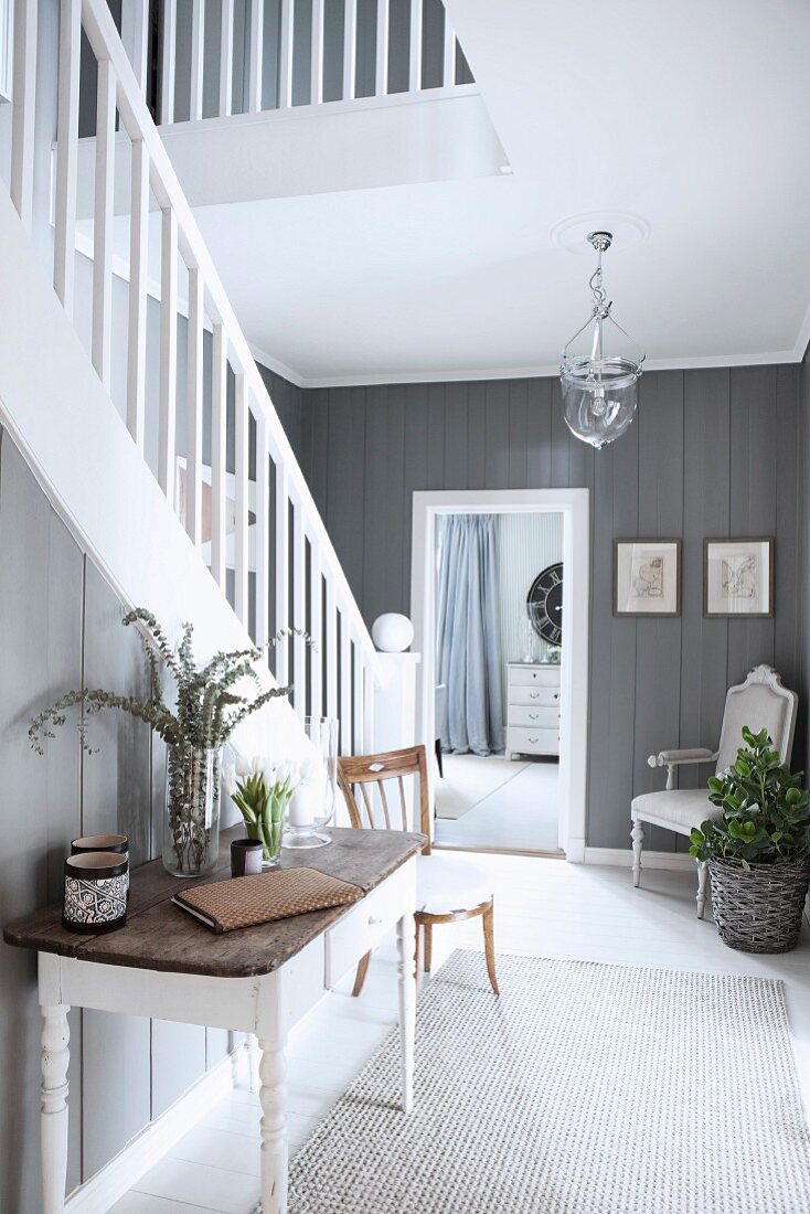 Elegant hallway with white-painted wooden staircase and grey wood-clad walls