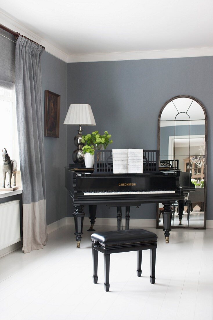 Schwarzes Klavier und Klavierhocker auf weißem Dielenboden