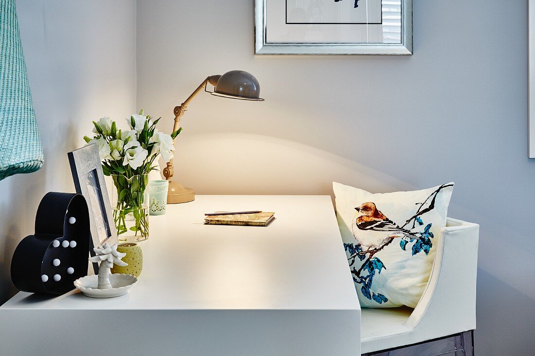 White desk lit by retro table lamp and chair with cushion