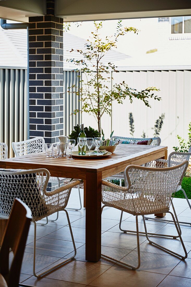 Classic-style mesh chairs around wooden table on roofed terrace
