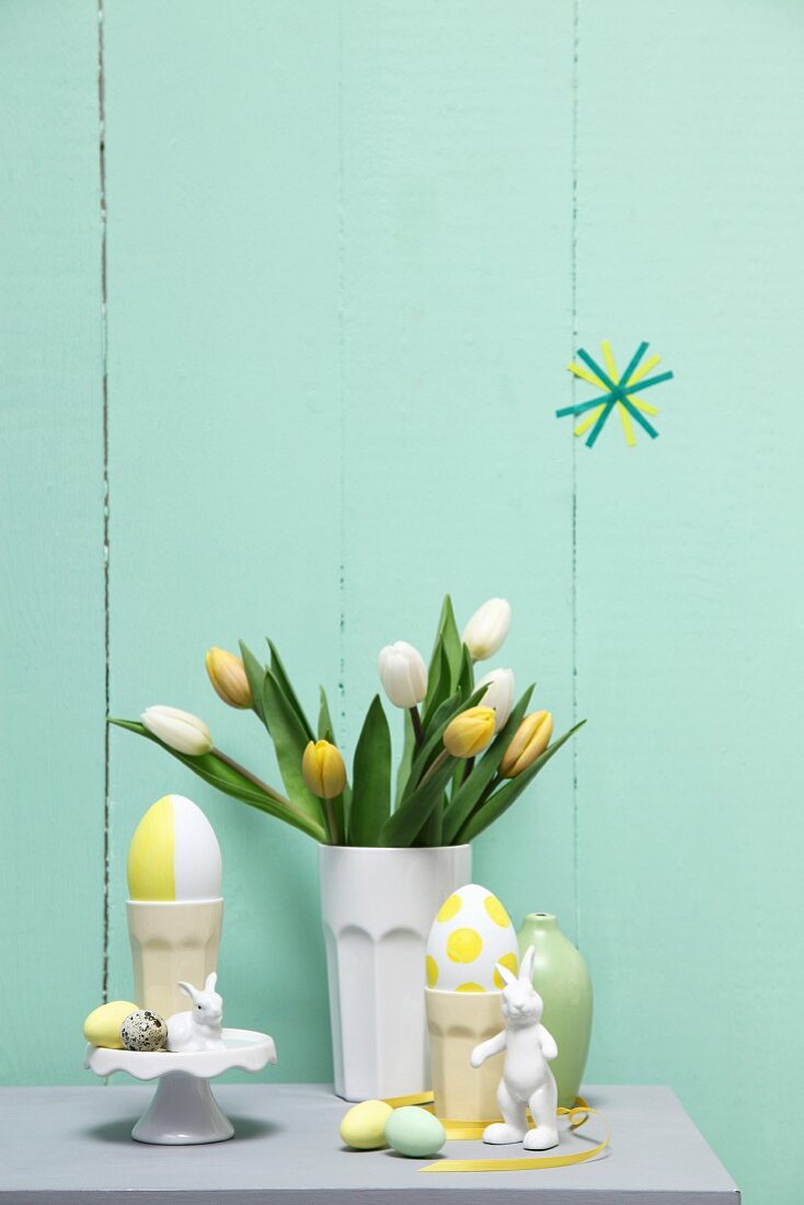 Pastel Easter arrangement; tulips in ceramic beaker, eggs and rabbit ornaments