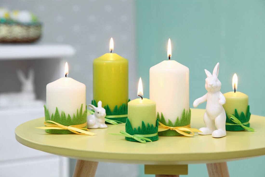 Easter arrangement in shades of green; candles with grass motif trim and rabbit ornaments on small, round table