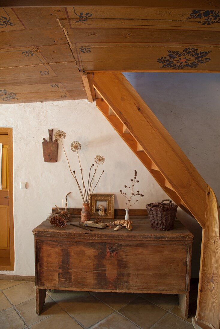 Hausflur mit rustikaler Holztruhe unter Treppenlauf und bemalte Holzdecke