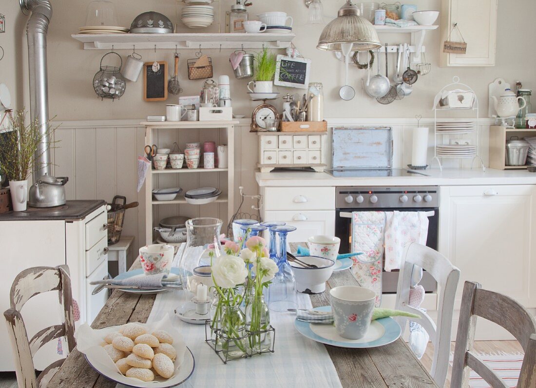 Kitchen-dining room decorated with vintage utensils and ranunculus on set wooden table