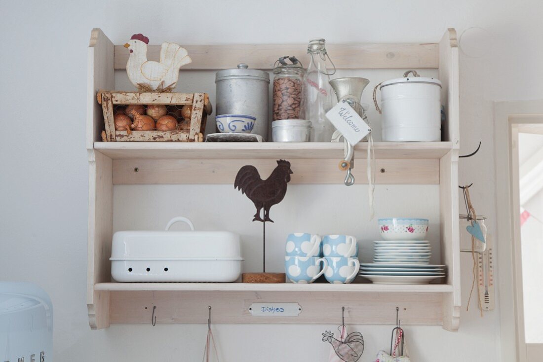 Pastel shabby-chic crockery and food stored in vintage-style jars and bottles on wall-mounted kitchen shelves