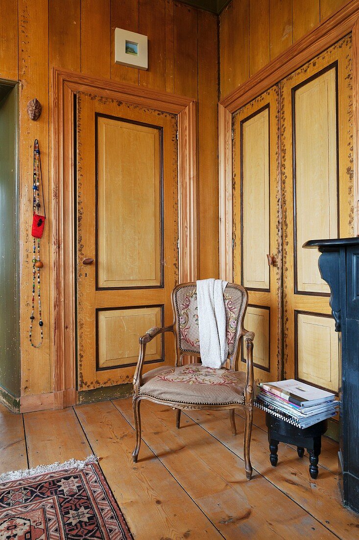 Stuhl im Rokokostil in Zimmerecke, neben Einbauschrank mit bemalten Türen