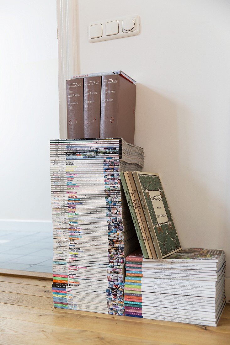 Zeitschriftenstapel mit Büchern am Boden