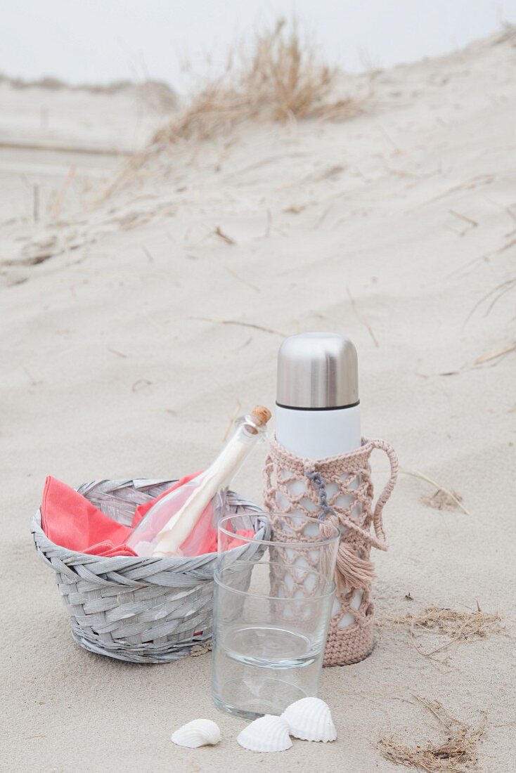 Beach picnic with thermos flask in pink crocheted cover