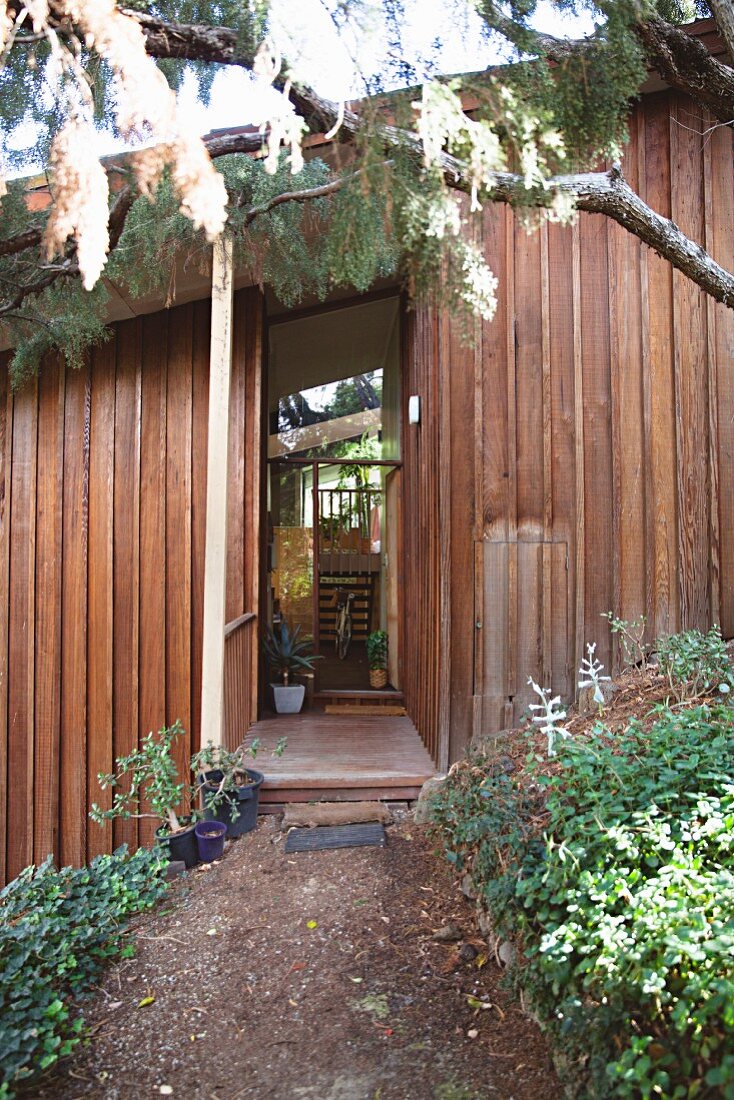 Blick vom Garten auf Redwood-Holzhaus mit offener Tür