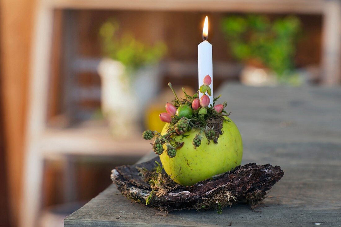 Brennende Kerze in dekorierten Apfel gesteckt