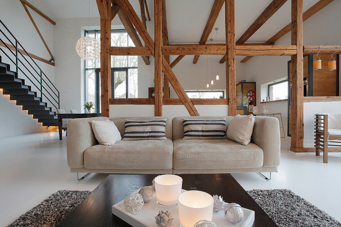 Open-plan living room with exposed wooden beams and modern furniture