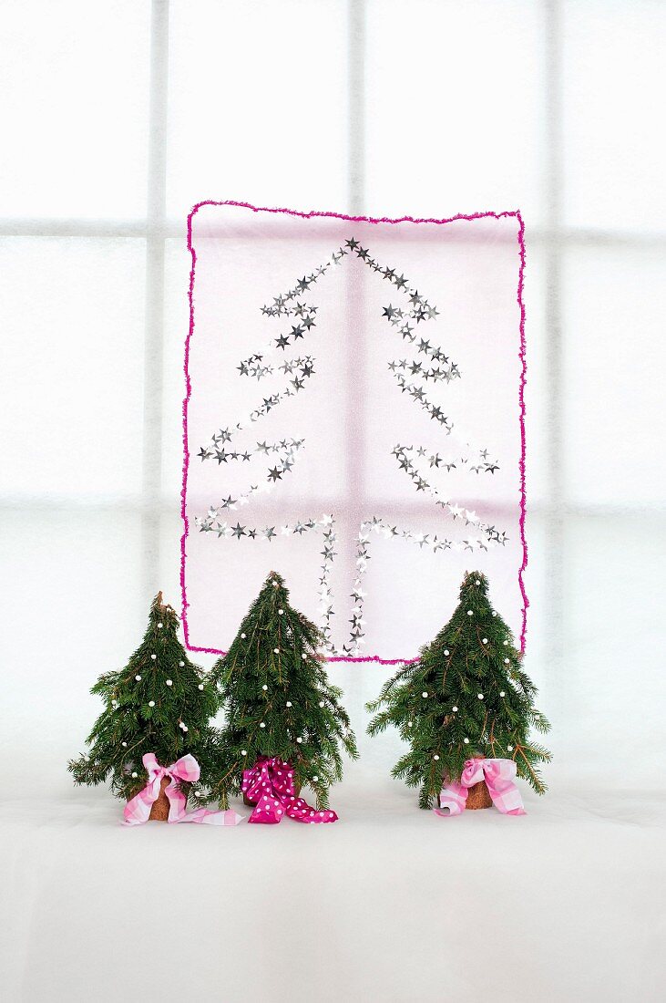 Tannenbaummotiv mit Glitzersternchen auf transparentem Stoff und Tannenbäumchen mit rosa Schleifenband