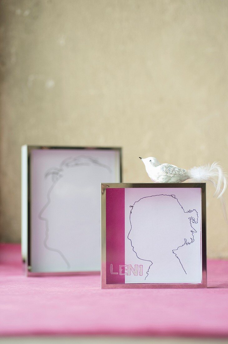 Hand-drawn silhouettes in chrome picture frames and bird ornament