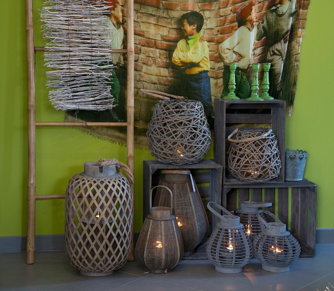 Various lanterns and wooden crates below wall-hanging with picture of children on green wall