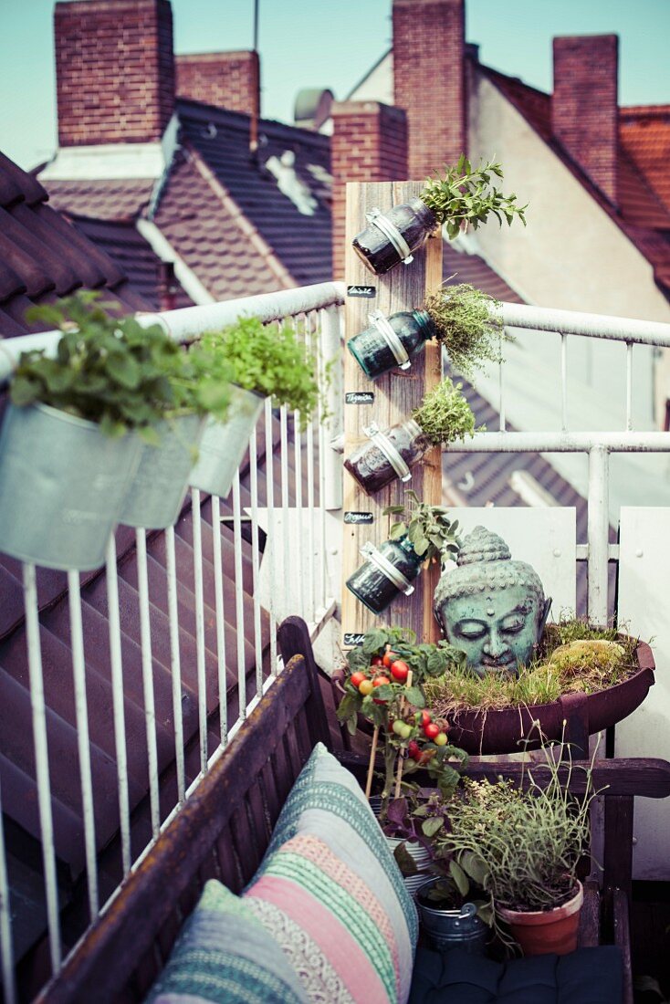 Head of Buddha and mason jar planters next to seating area on urban roof terrace