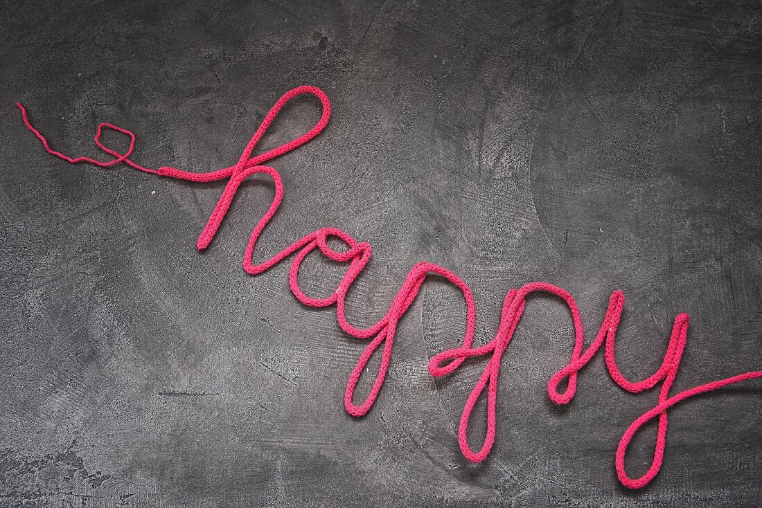 'Happy' Schriftzug aus pinkfarbenem Wollschlauch mit Drahtverstärkung