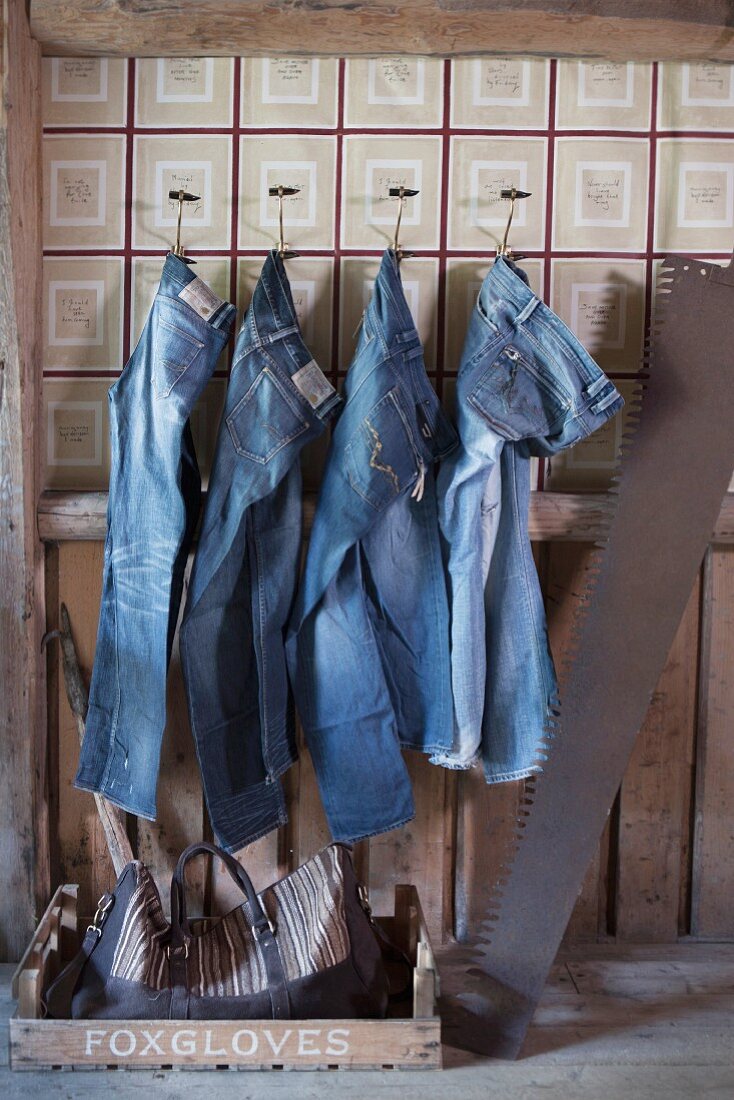 Jeans hanging from wall hooks in rustic interior