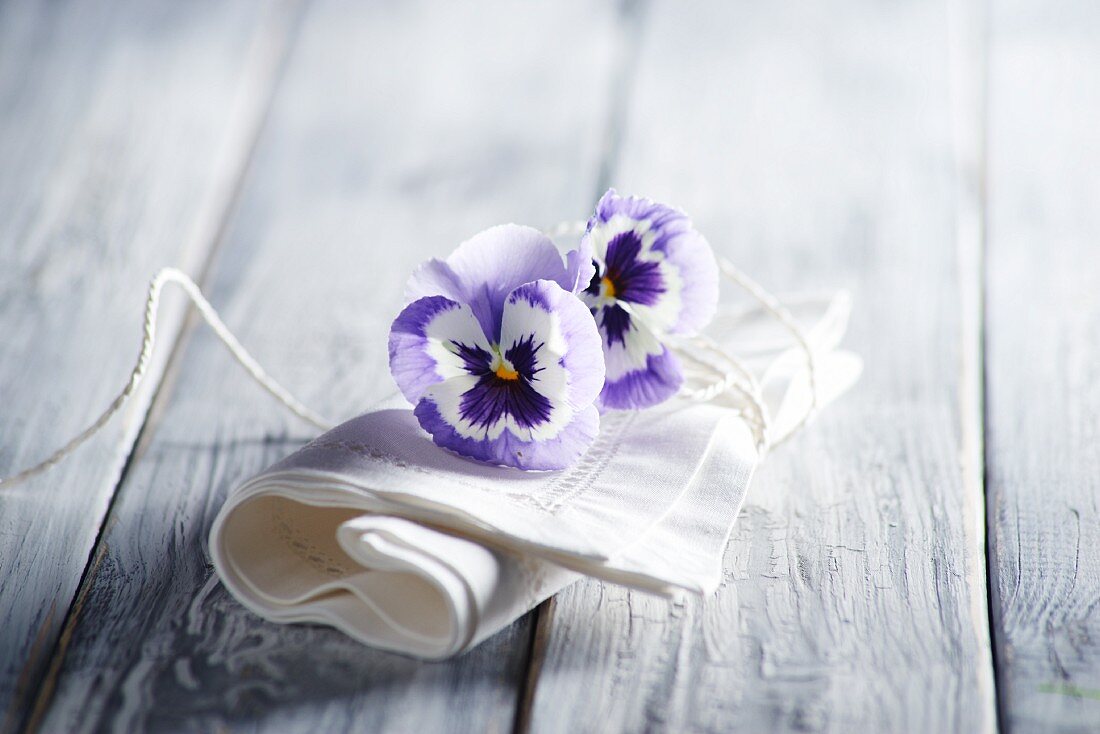 White linen napkin and violas on wooden surface