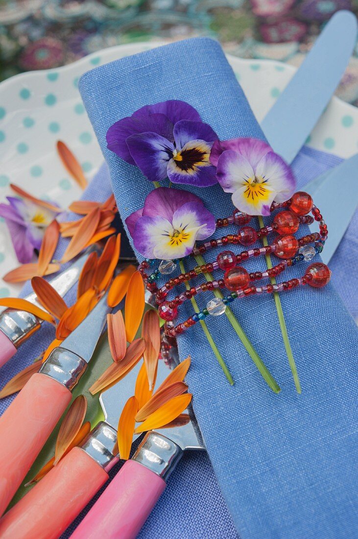 Violas on blue linen napkin tied with bead necklace