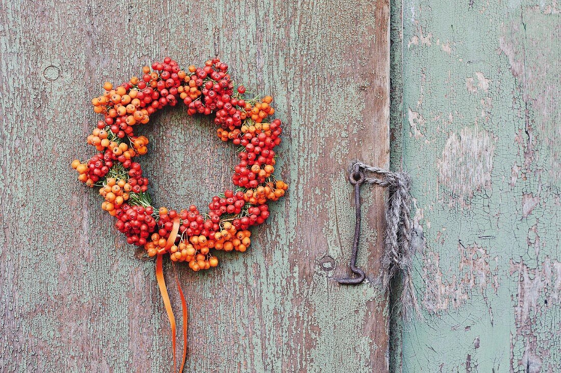 Kranz aus Vogelbeeren an verwitterter Holzwand