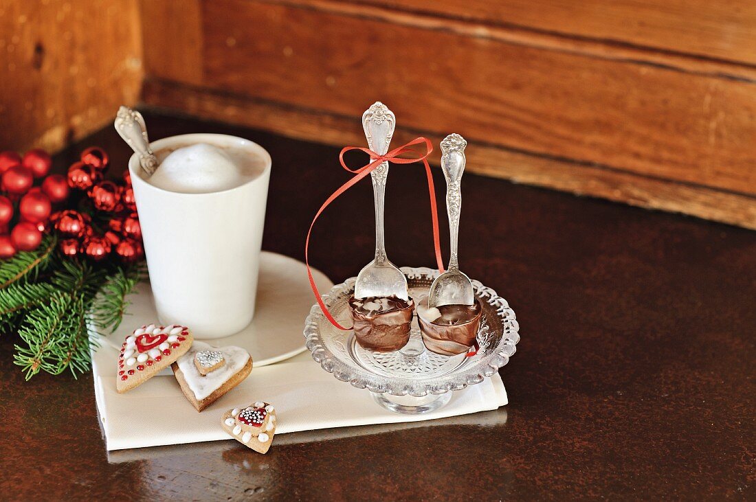 Edle Trinkschokolade am Löffel, Kaffeebecher und Weihnachtsplätzchen