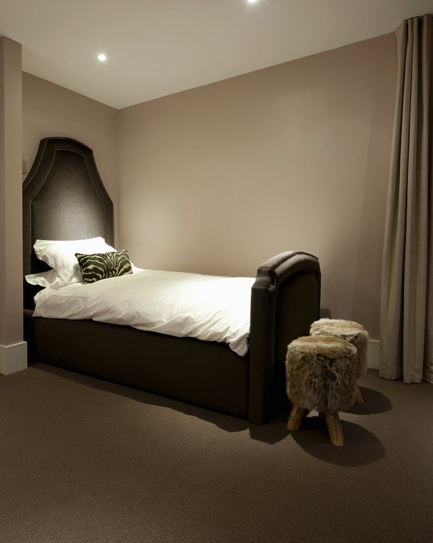 Dreibeinige Fellhocker und imposantem Einzelbett im Schlafzimmer mit gedeckter Farbgebung