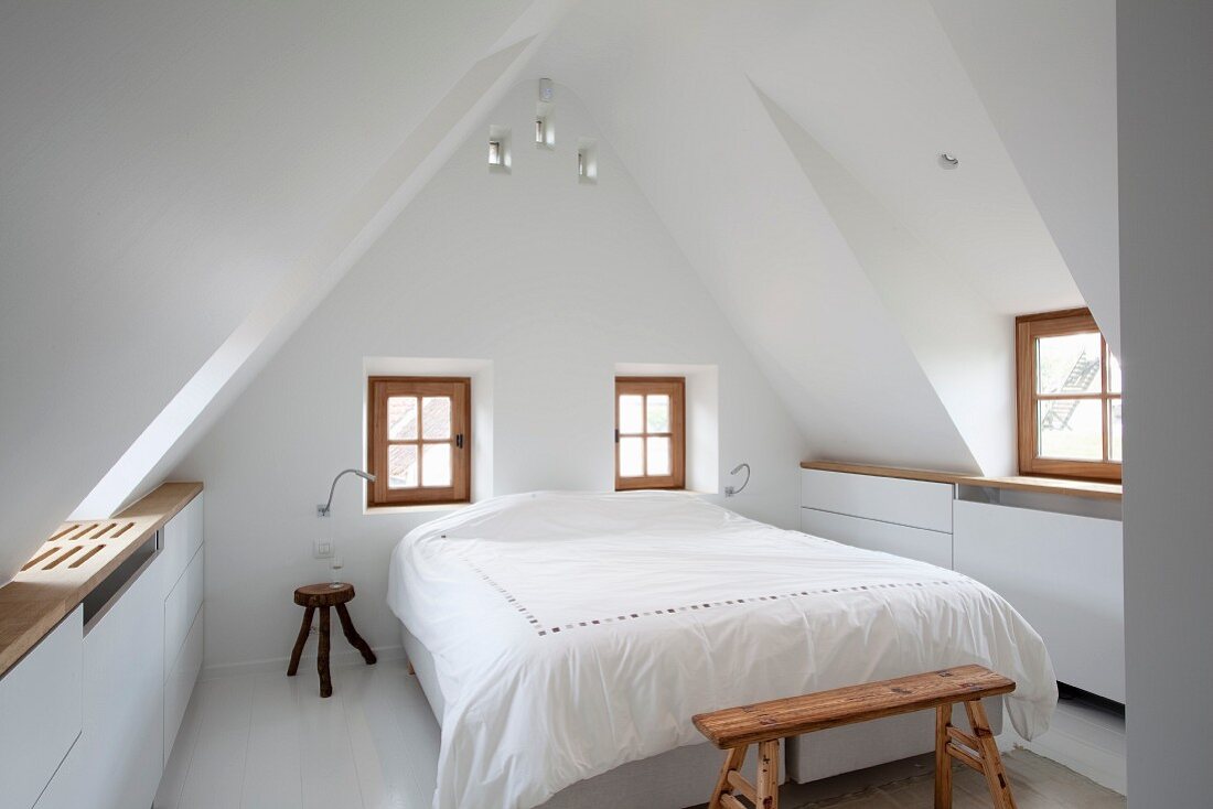 Weißes Schlafzimmer mit Sprossenfenstern im Dachgeschoss