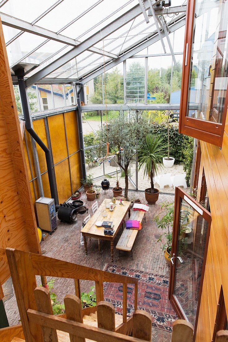 View from gallery down onto dining area in converted former greenhouse with brick floor