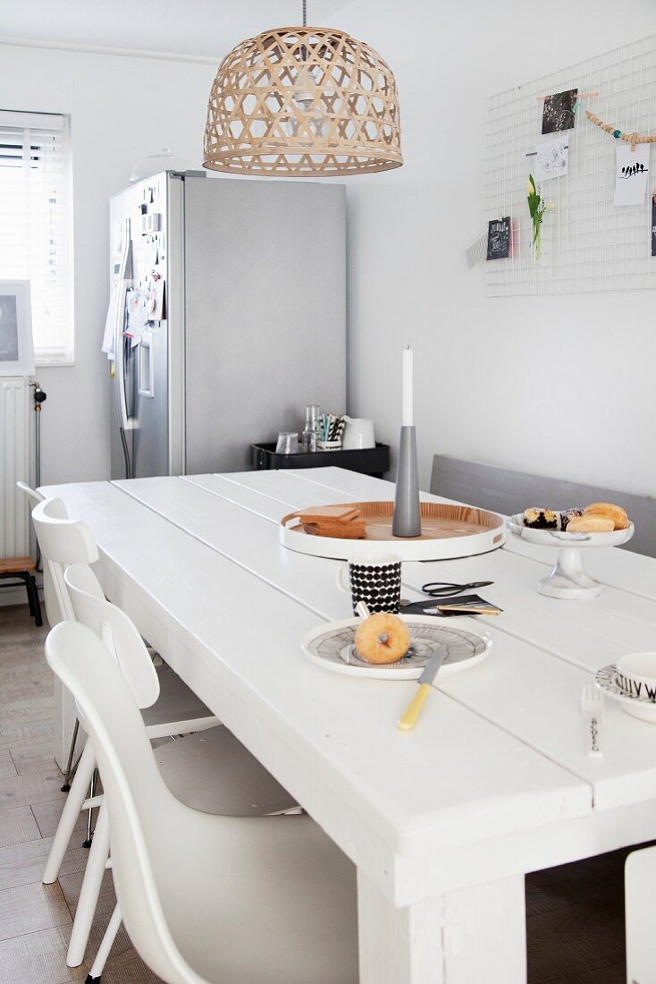 Weiß lackierter Massivholztisch, darüber Korblampenschirm in Wohnküche