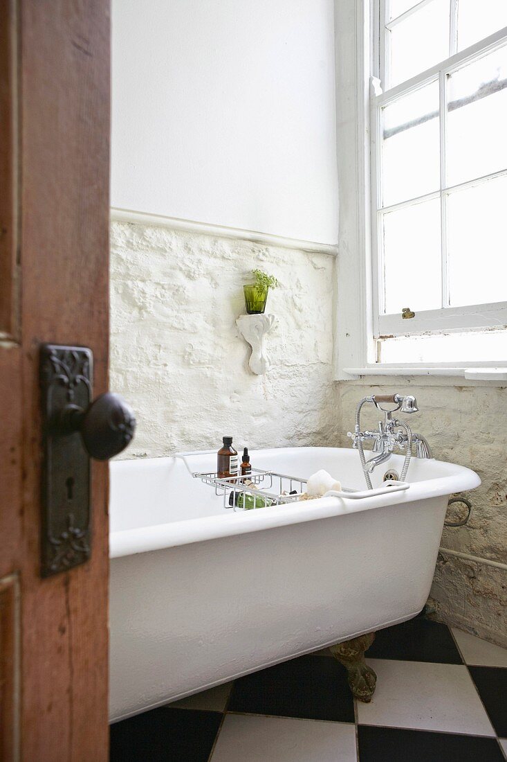 Bathroom with vintage free-standing bathtub against exposed stone wall
